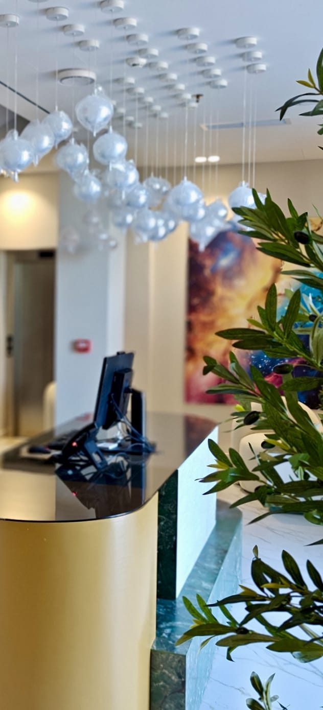 Reception — bancone in marmo verde e luci sospese